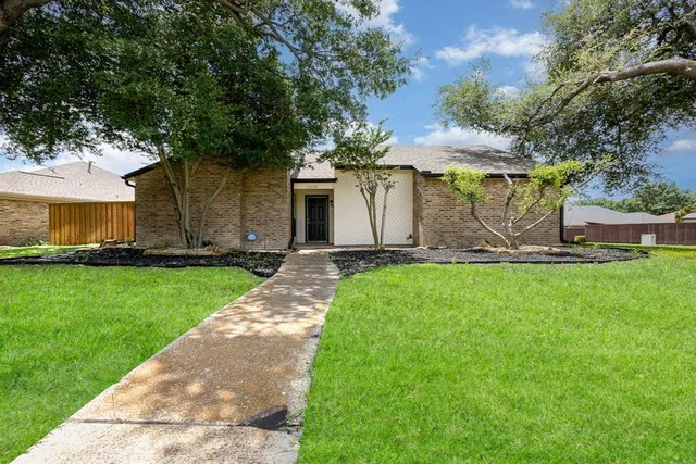 a front view of a house with a garden and tree