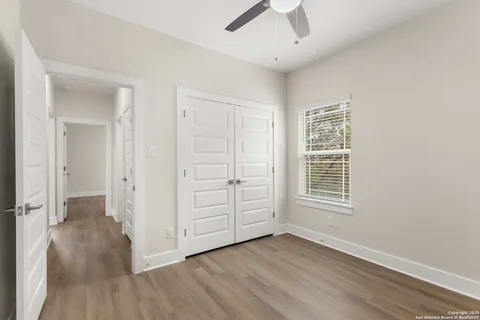 an empty room with wooden floor cabinet and windows