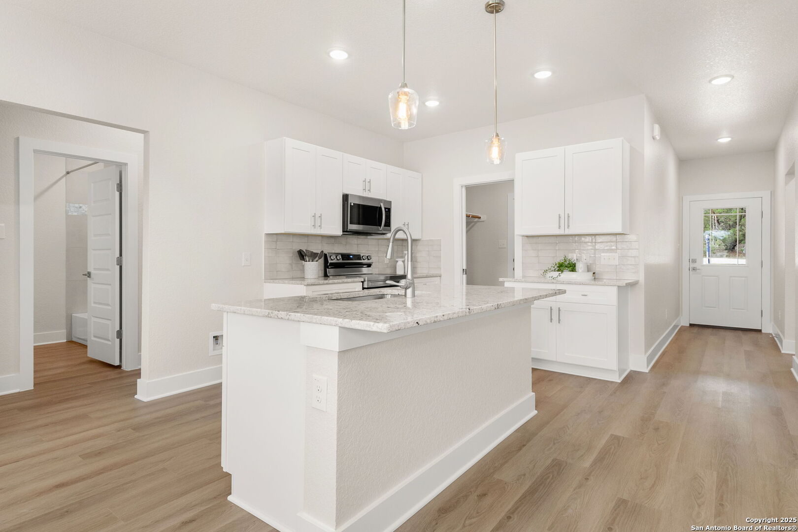 952 Rimrock Cove Spring Branch, TX 78070 - Photo 7 of 39 a kitchen with kitchen island white cabinets and stainless steel appliances