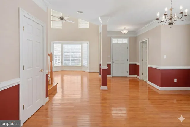 a view of an empty room with wooden floor and windows