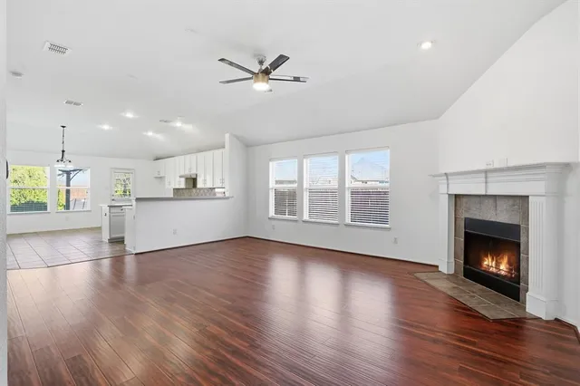 a view of an empty room with wooden floor fireplace and a window