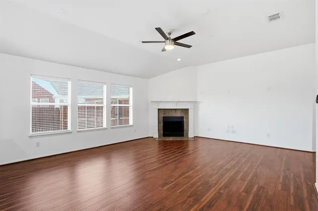 an empty room with wooden floor cabinet and windows