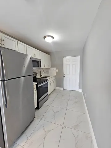 a kitchen with a refrigerator a stove top oven and cabinets