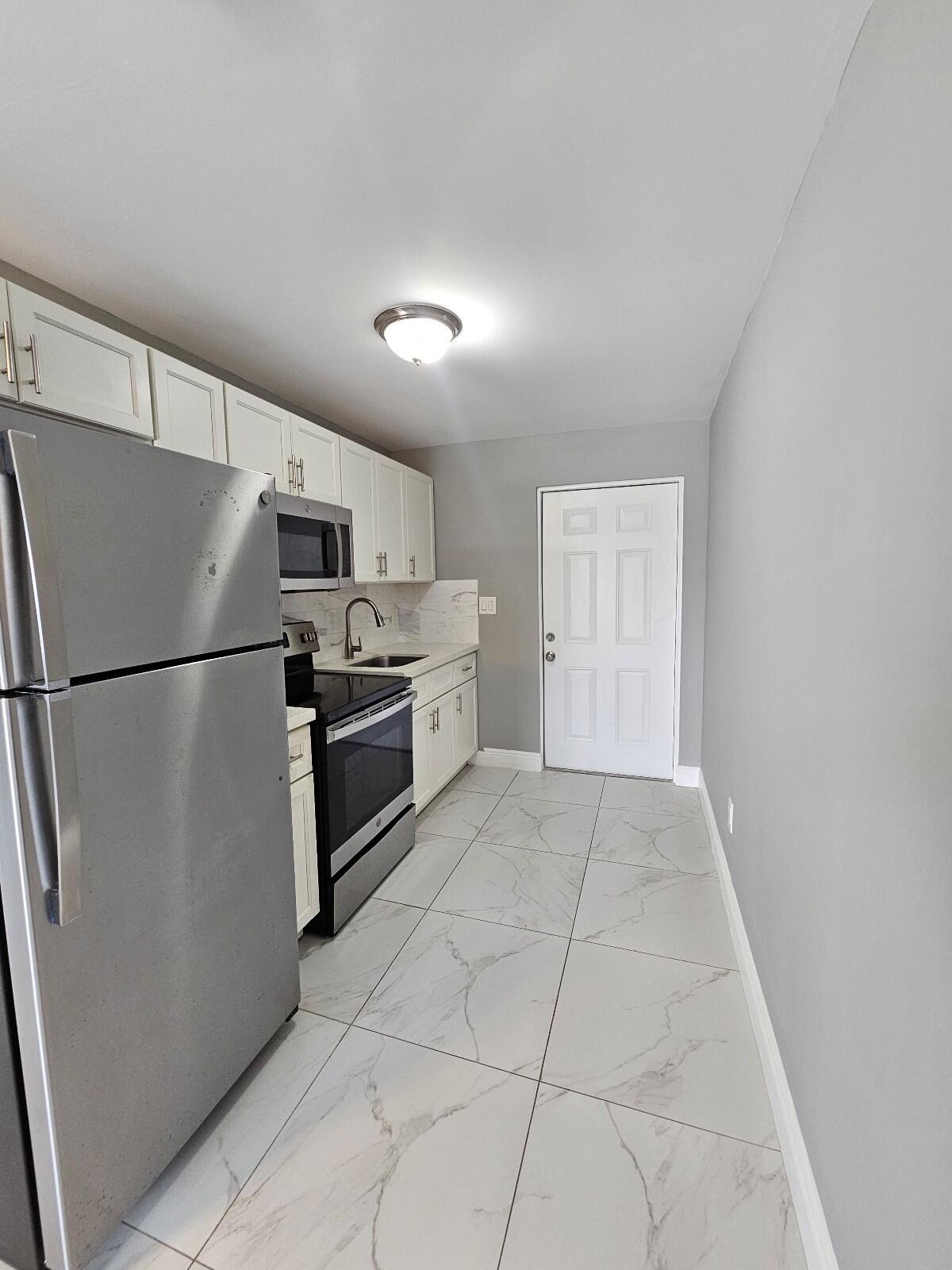 933 West 7th Street, Unit C Riviera Beach, FL 33404 - Photo 4 of 16 a kitchen with a refrigerator a stove top oven and cabinets