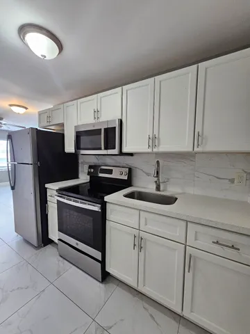 a kitchen with stainless steel appliances granite countertop a sink a stove a refrigerator a microwave and cabinets