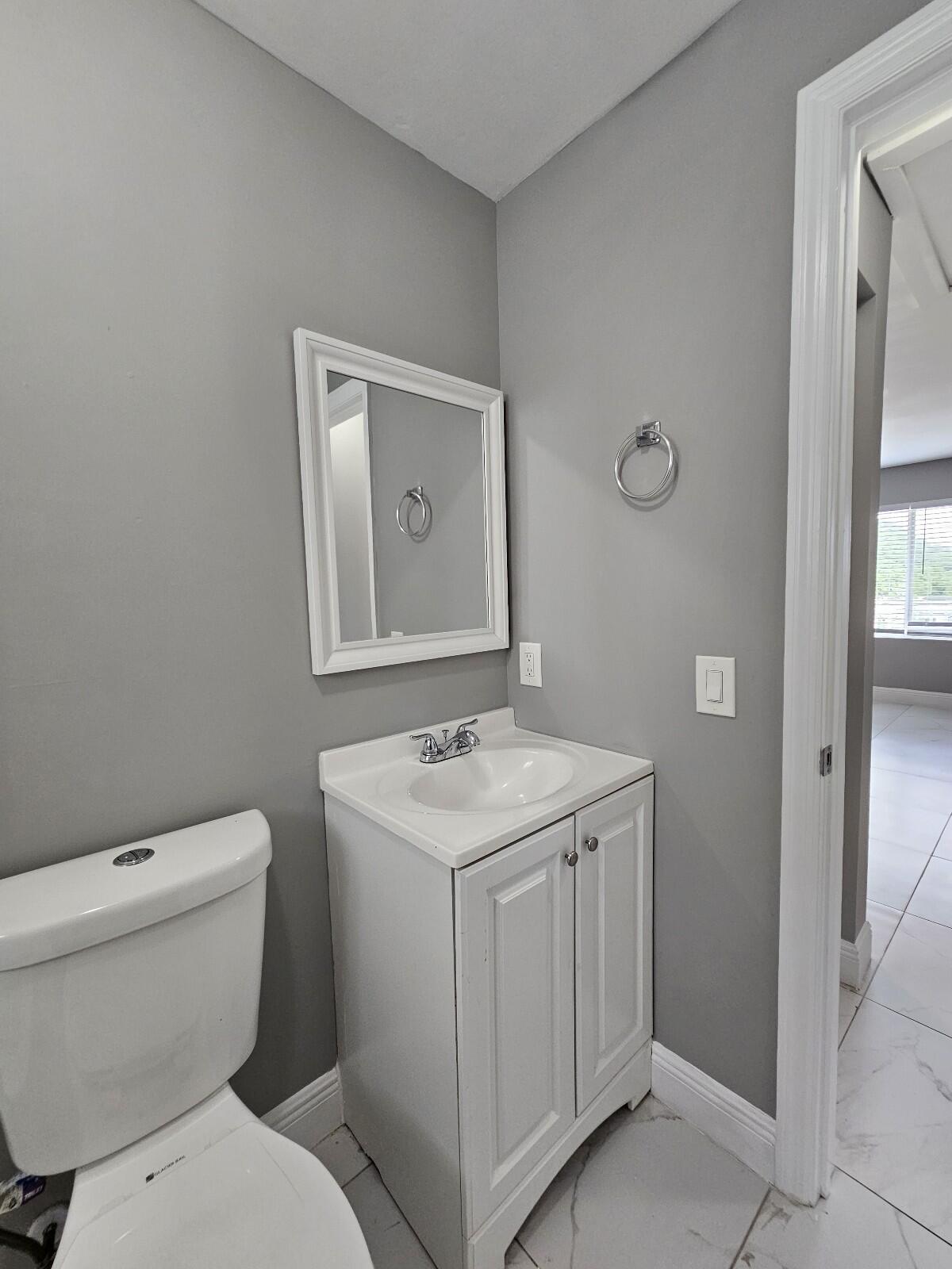 933 West 7th Street, Unit C Riviera Beach, FL 33404 - Photo 10 of 16 a bathroom with a toilet sink and mirror
