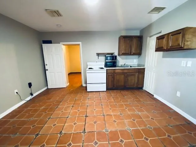 a room with kitchen island granite countertop a stove top oven a sink and a granite counter top