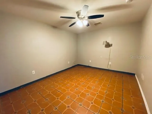 an empty room with a ceiling fan and window
