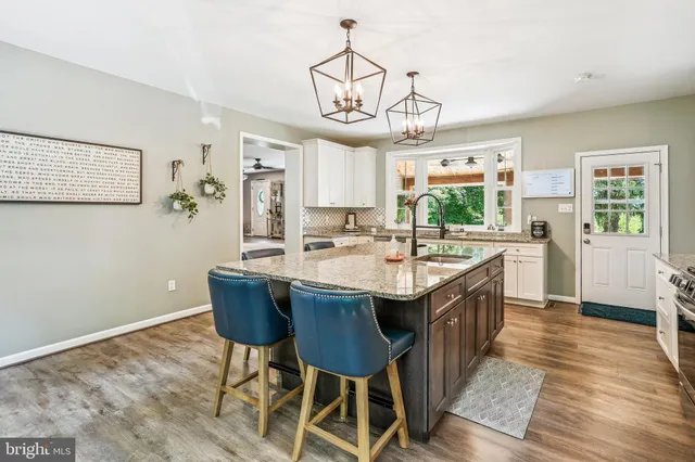 a kitchen with stainless steel appliances granite countertop a sink a stove a refrigerator dining table and chairs