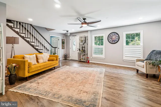a view of a livingroom with wooden floor and a ceiling fan