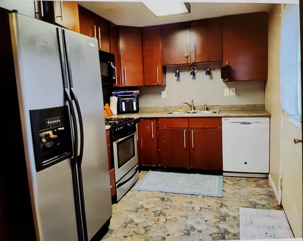 a kitchen with stainless steel appliances granite countertop a refrigerator a stove and a sink