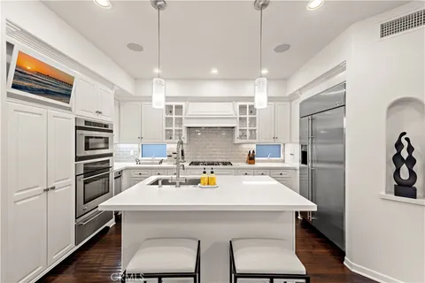 a kitchen with a sink a refrigerator and chairs