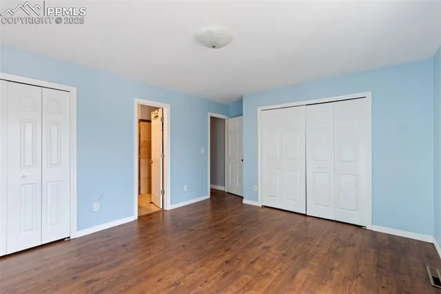 a view of an empty room with wooden floor and closet