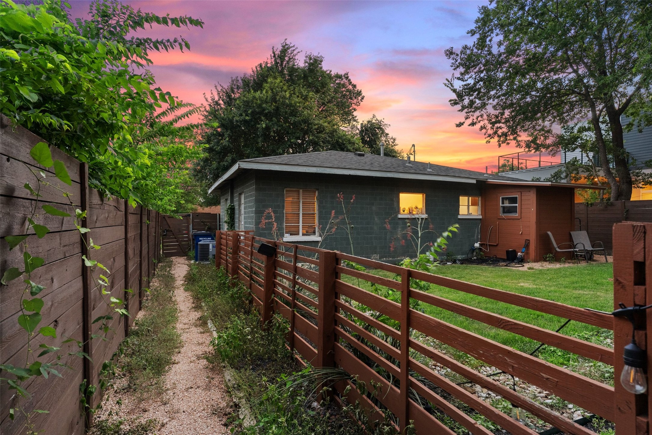 412 West Croslin Street Austin, TX 78752 - Photo 35 of 36 A deep sunset sky casts a warm glow over a quaint home with a private yard and wooden fences.