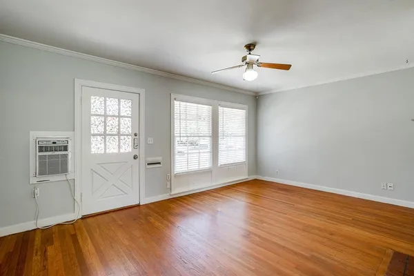 an empty room with wooden floor fan and windows