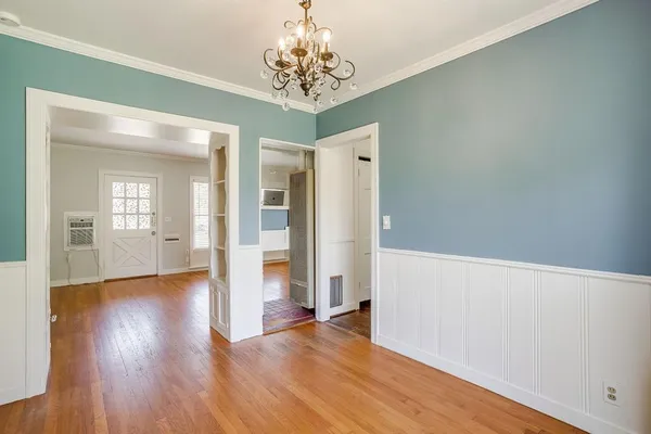 a view of a hallway with wooden floor and a chandelier