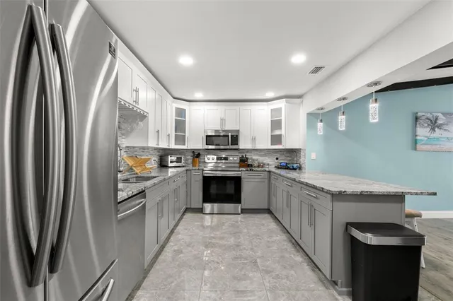 a large kitchen with stainless steel appliances granite countertop a stove top oven a sink and dishwasher a refrigerator with wooden floor