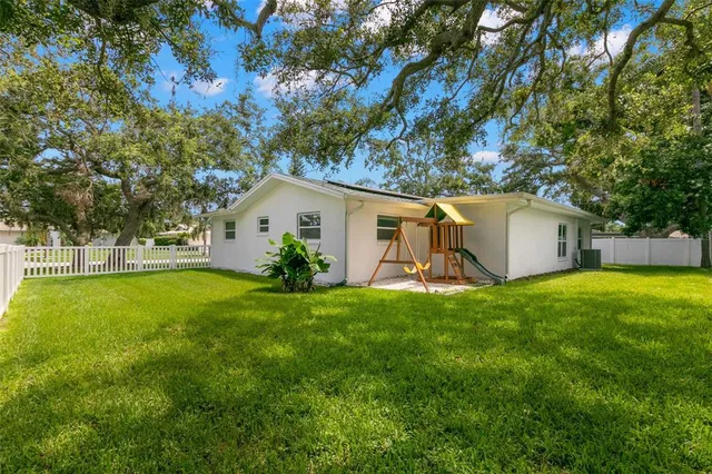 a view of a white house with a big yard and large tree