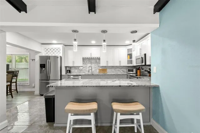 a kitchen with stainless steel appliances granite countertop a table chairs and a refrigerator