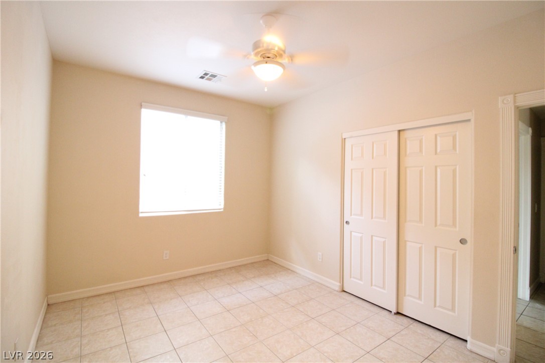 754 Rise Canyon Drive Henderson, NV 89052 - Photo 13 of 34 A quiet bedroom featuring tiled flooring and convenient sliding closet doors.