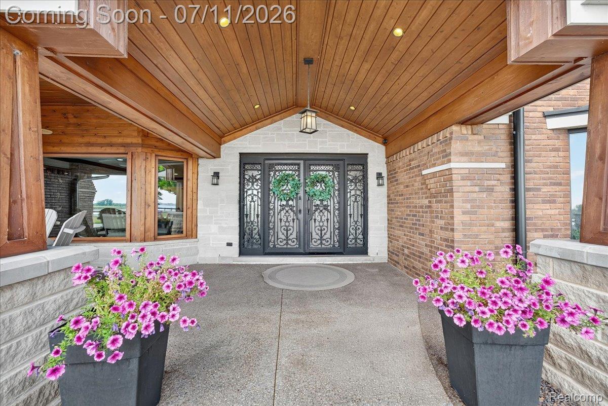 23750 East River Road Grosse Ile, MI 48138 - Photo 2 of 54 Ornate black iron double entry doors set against a white stone facade