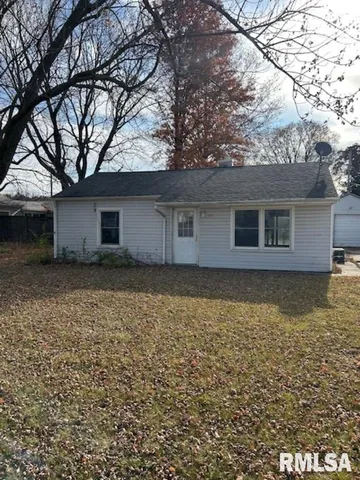 a backyard of a house with large trees and wooden fence