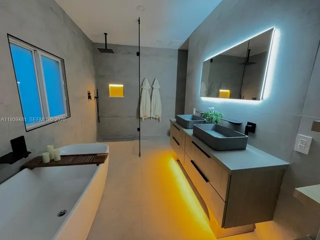 a bathroom with a tub a double vanity sink and mirror