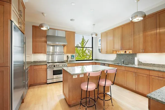 a kitchen with stainless steel appliances granite countertop a stove top oven a sink dishwasher a dining table and chairs with wooden floor