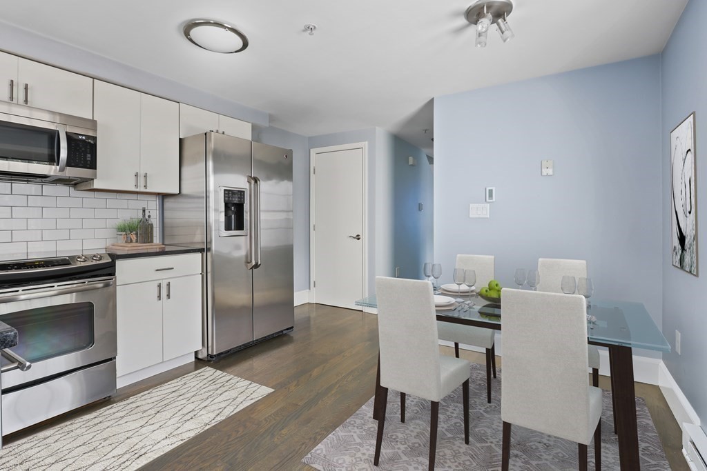 a kitchen with stainless steel appliances a dining table chairs microwave and sink