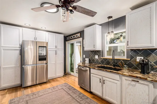 a kitchen with stainless steel appliances a refrigerator a sink and white cabinets