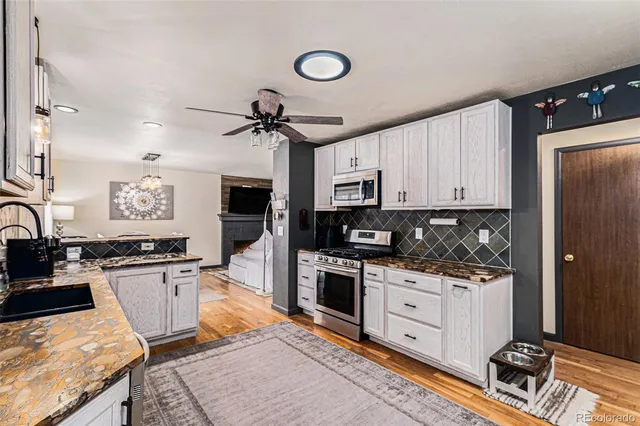 a kitchen with stainless steel appliances granite countertop a stove top oven a sink a counter space and cabinets