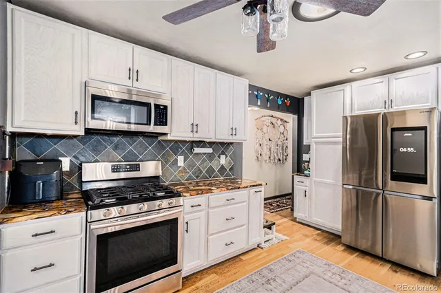 a kitchen with stainless steel appliances white cabinets white stove a microwave and a refrigerator