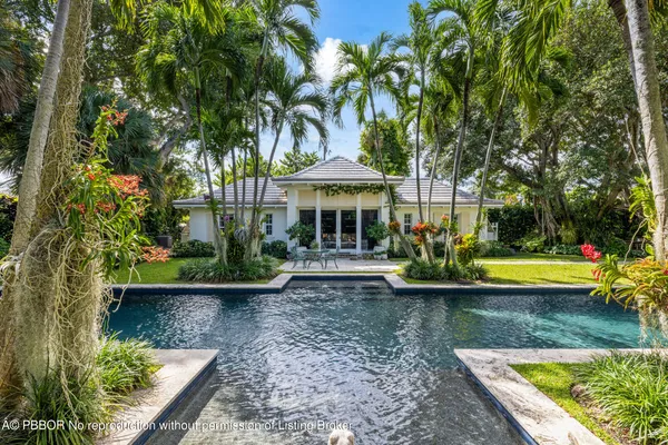 a view of swimming pool with lawn chairs and plants