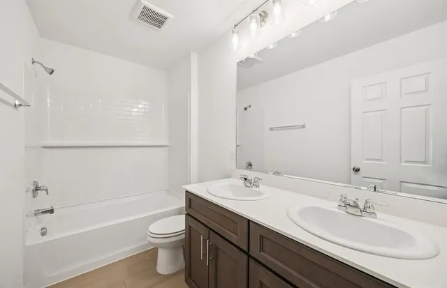 a bathroom with a double vanity sink toilet mirror and bathtub