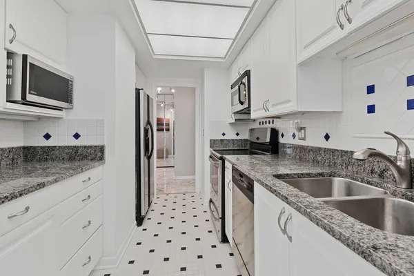 a kitchen with granite countertop a sink dishwasher a refrigerator and cabinets