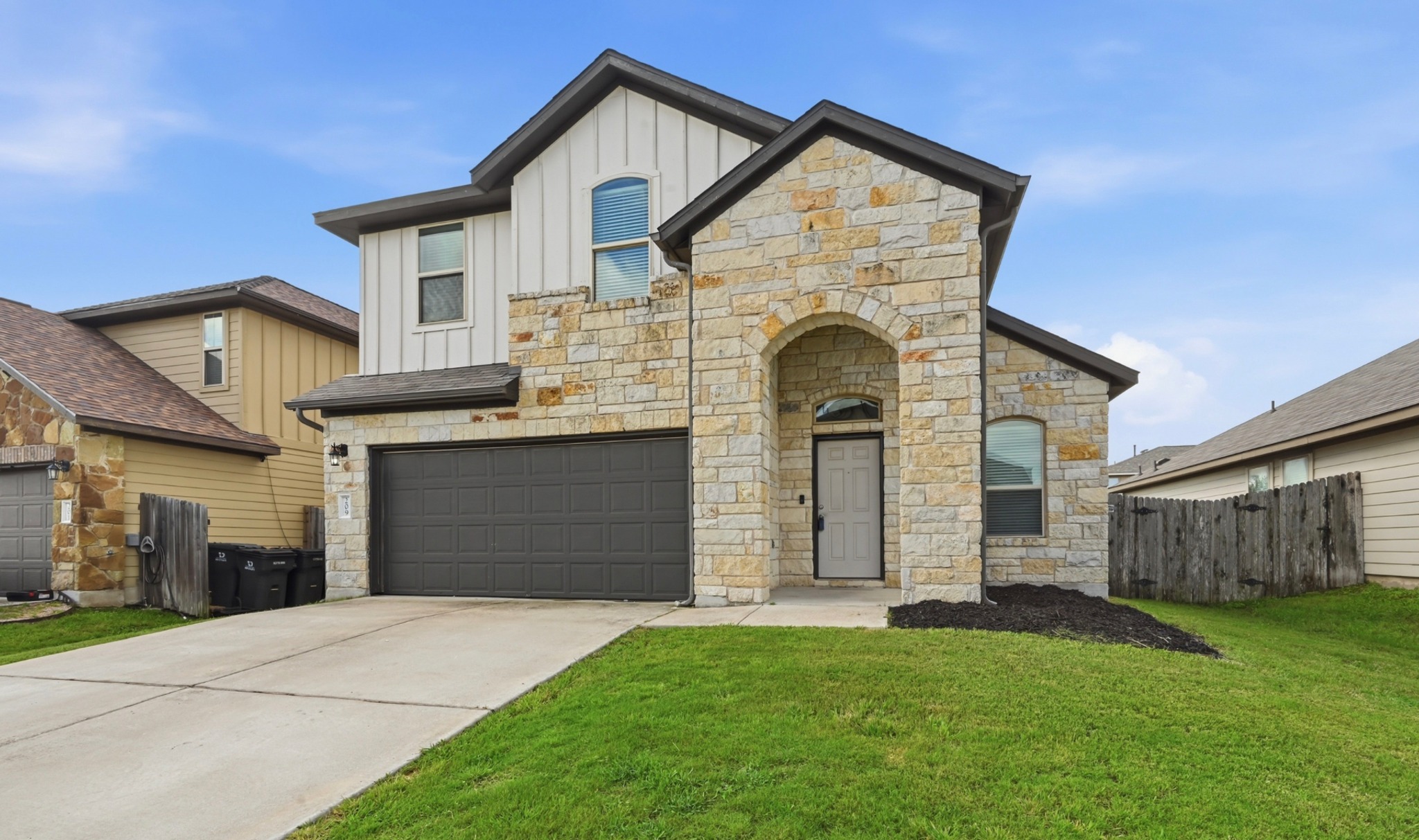 209 Noddy Road Buda, TX 78610 - Photo 1 of 30 Beautiful two story home featuring an arched entry, two-car garage, and a blend of vertical siding with dark trim accents