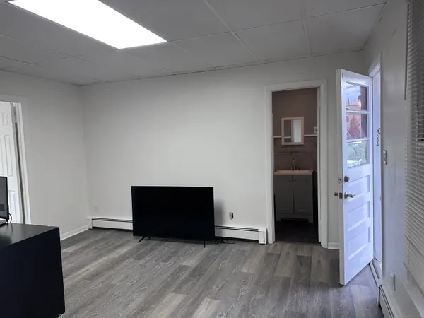 a view of an empty room with wooden floor and a fireplace