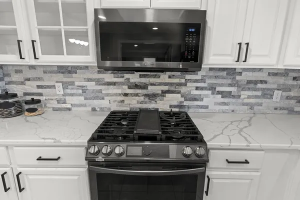 a close view of a stove a microwave and cabinets in the white kitchen