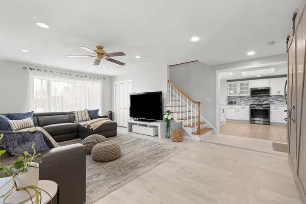 a living room with furniture and a flat screen tv with kitchen view