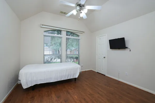 a bedroom with a bed and a flat tv screen on dresser