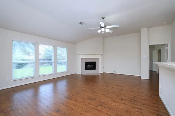 a view of an empty room with a window and wooden floor