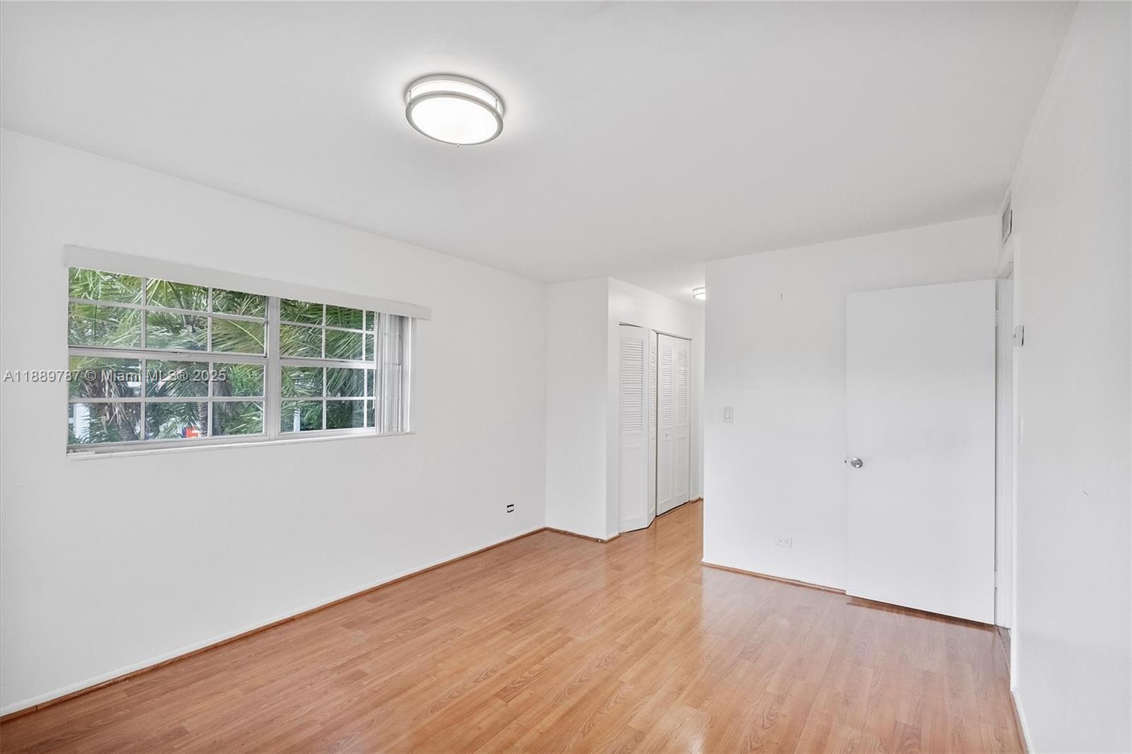8107 Southwest 72nd Avenue, Unit 201E Miami, FL 33143 - Photo 11 of 29 a view of an empty room with wooden floor and a window