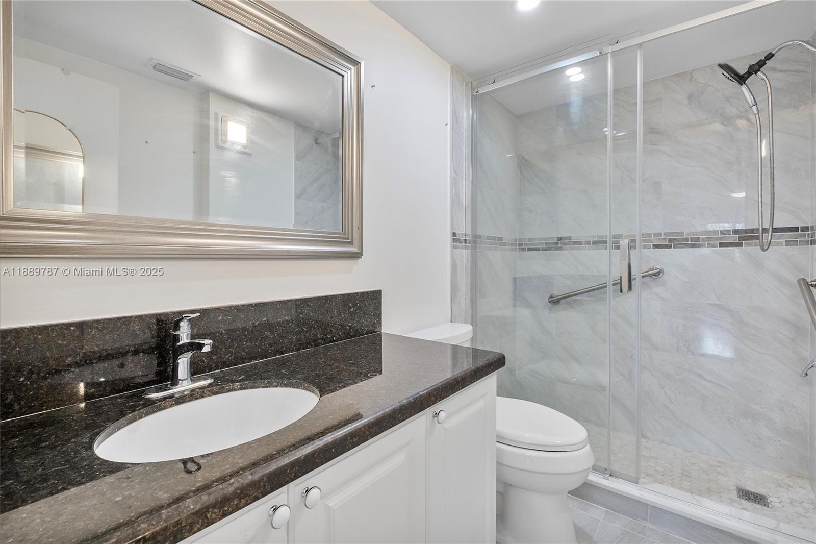 8107 Southwest 72nd Avenue, Unit 201E Miami, FL 33143 - Photo 12 of 29 a bathroom with a granite countertop sink mirror vanity and toilet