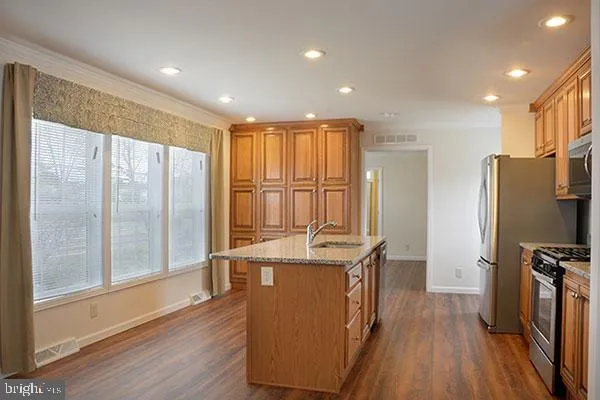 a kitchen with stainless steel appliances granite countertop a refrigerator a sink and a stove with wooden floor