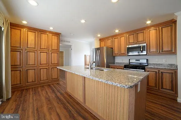 a kitchen with stainless steel appliances granite countertop a refrigerator a stove top oven a sink and dishwasher with wooden floor