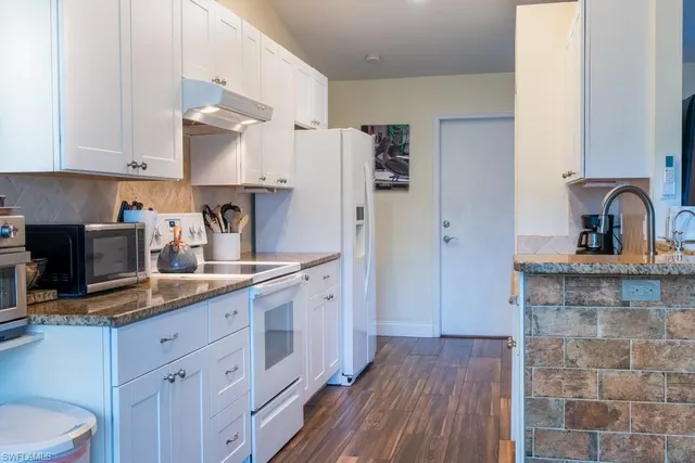 a kitchen with a sink dishwasher a refrigerator and cabinets with wooden floor