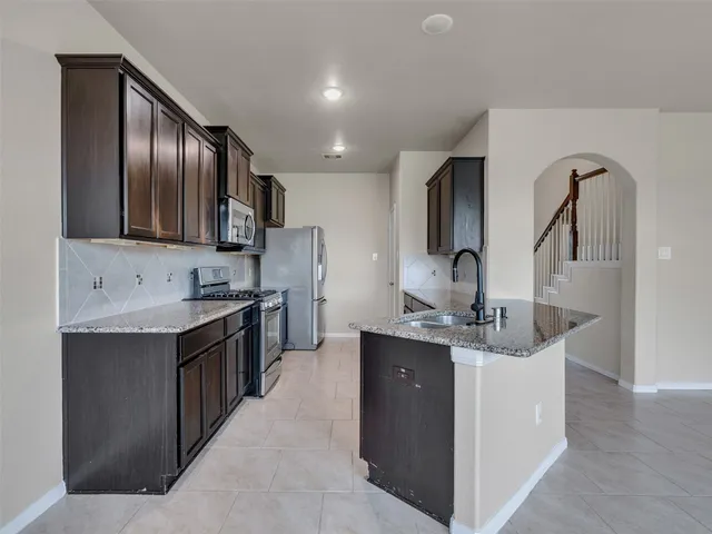 a kitchen with stainless steel appliances granite countertop a sink stove and refrigerator