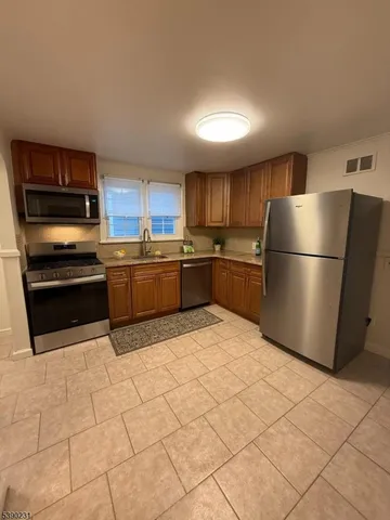 a kitchen with granite countertop a refrigerator and a stove top oven
