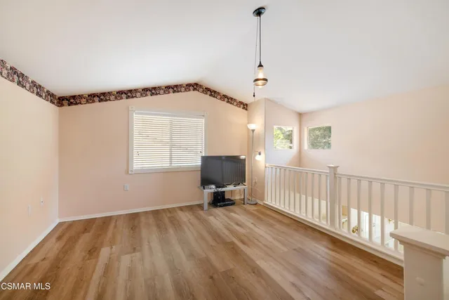 a view of a room with wooden floor mirror and windows