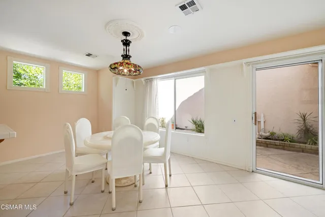 a dining room with chandelier front door and wooden floor